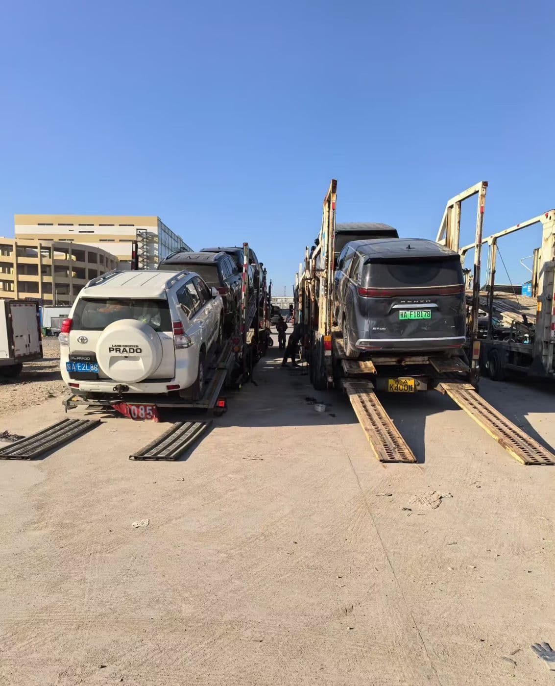 SUVs and sedans loaded onto car carriers at a vehicle yard