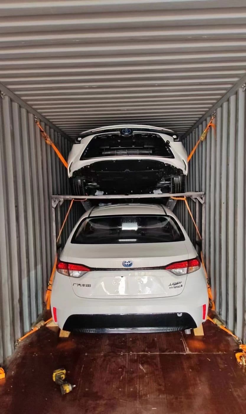 Two sedans double-stacked on a steel frame inside a 40-foot container